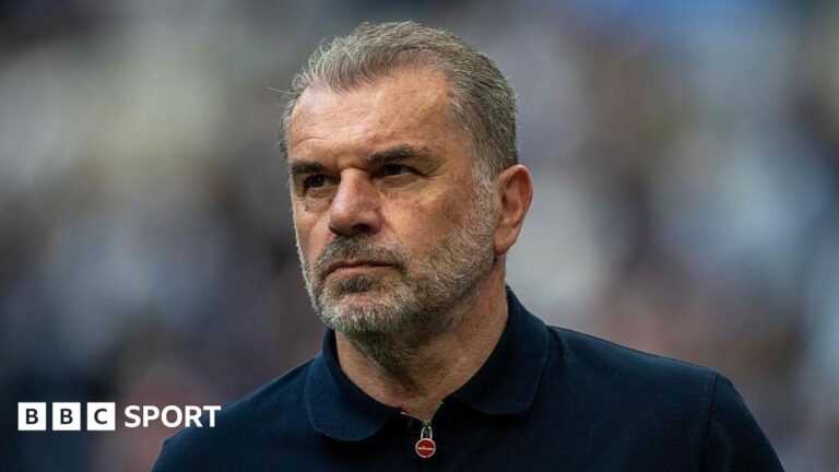 Tottenham ‘not a big club’, says former manager Ange Postecoglou Close-up of Ange Postecoglou. He has short grey hair, brushed away from his face, and a grey beard. He is wearing a navy top which has a zip fastening at the collar.