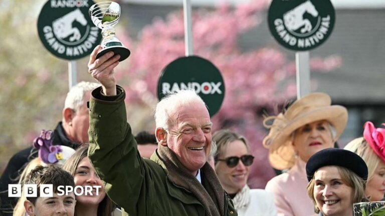 Grand National 2026: I Am Maximus wins a fourth race at Aintree for Willie Mullins Willie Mullins smiling and holding a trophy in the air