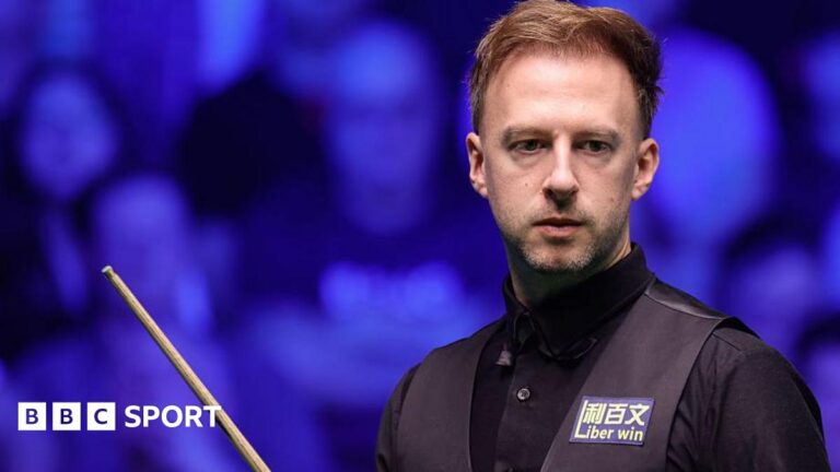 Tour Championship: Judd Trump beats Neil Robertson to reach final in Manchester Judd Trump in black shirt and waistcoat carrying a snooker cue