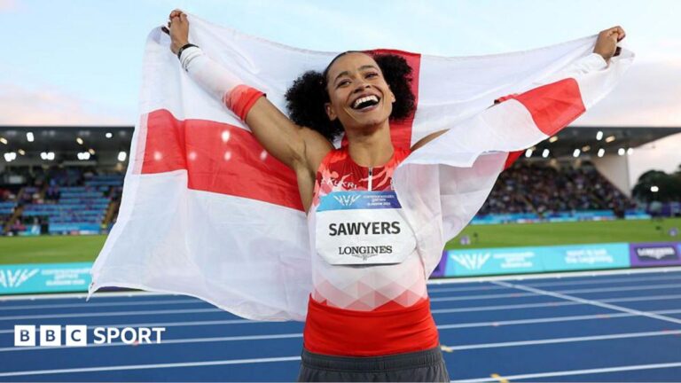 Commonwealth Games 2026: England’s Sawyers puts heartbreak to secure long jump gold A smiling Jazmin Sawyers in a red and white Team England vest raises her arms to the skies whiles draped in the England flag