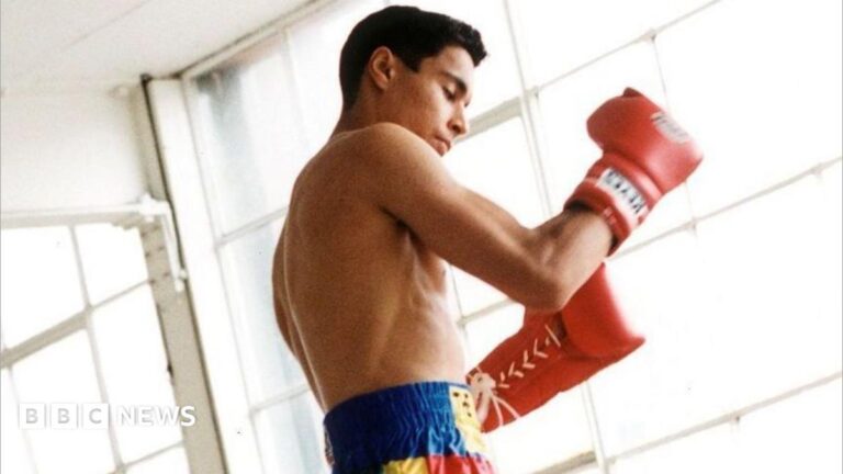 How the heir to Prince Naseem never became king – Daniel Teasdale’s story A young boy shadow boxed in what looks like an empty warehouse with bright natural light shining into the room. He is wearing blue, yellow and red shorts and red gloves.